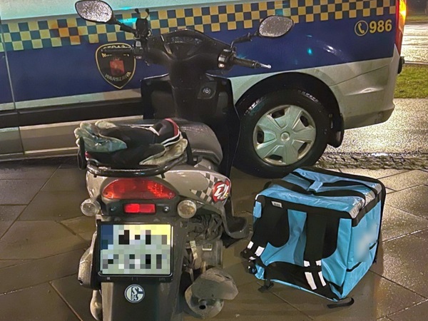 Skuter z torbą dostawczą skonfiskowany przez policję. Tablica rejestracyjna częściowo zasłonięta.