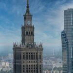 Panorama Warszawy z wieżą zegarową Pałacu Kultury i Nauki oraz nowoczesnymi wieżowcami.