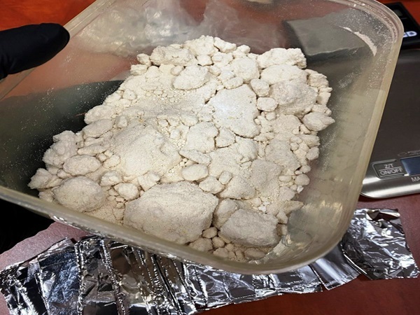 Duża ilość skonfiskowanej metamfetaminy w przezroczystym plastikowym pojemniku.