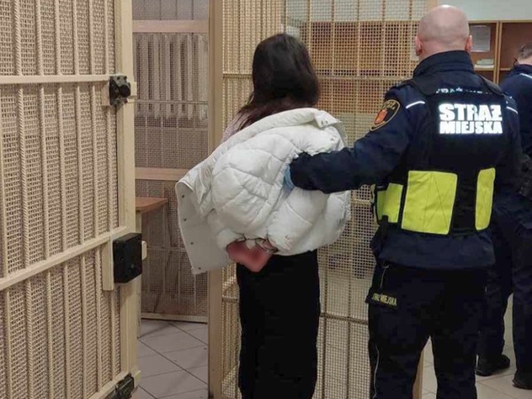 Policjant eskortujący kobietę w areszcie.