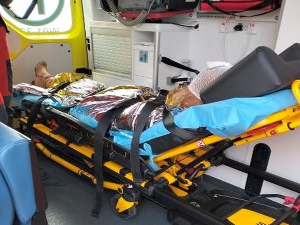 Pacjent na noszach w karetce, owinięty kocem termicznym.