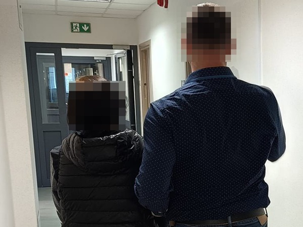 Dwie osoby, zwrócone tyłem do kamery, idą korytarzem.