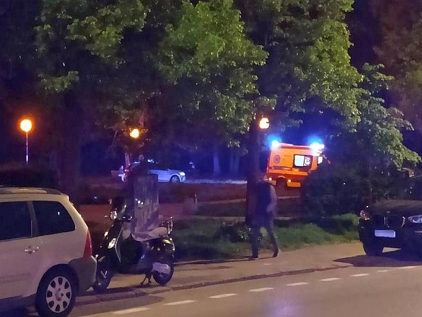 Nocna scena ratunkowa z udziałem karetki pogotowia, samochodów i skutera.