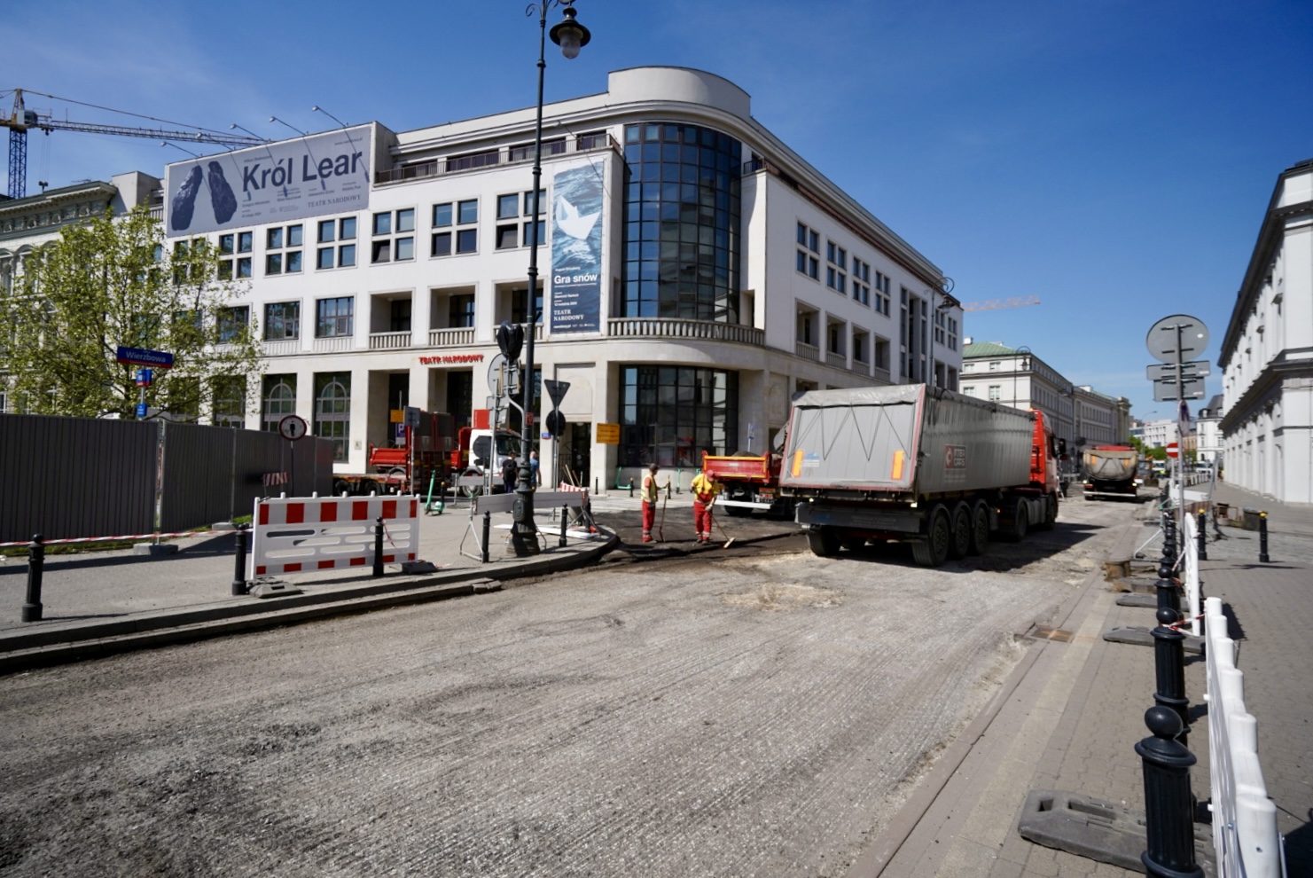 Budowa drogi w pobliżu Teatru Narodowego w Warszawie. Uczestniczą w niej ciężarówki i robotnicy.