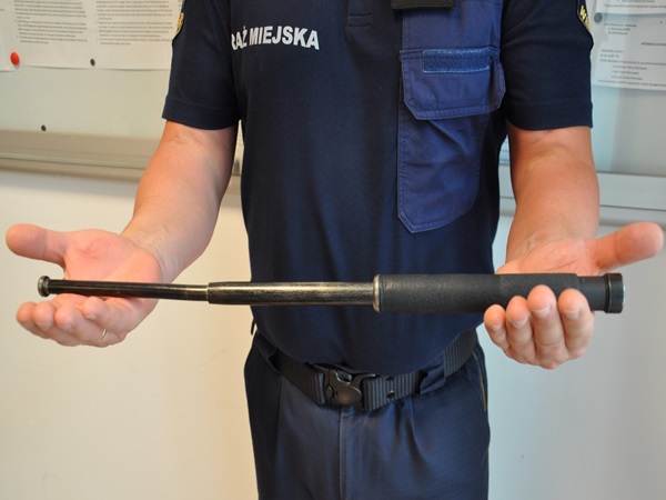 Policjant pokazujący pałkę teleskopową