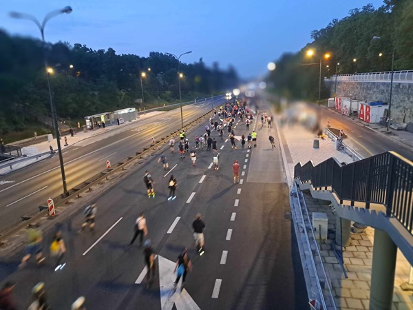 Duża grupa ludzi jeżdżących na rolkach na miejskiej drodze o zmierzchu.