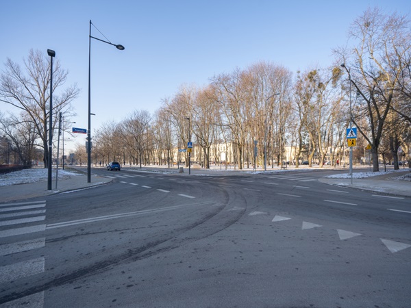 Puste skrzyżowanie z drzewami i samochodem, zimowa scena