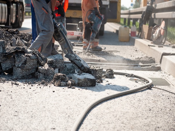 Robotnicy drogowi używają młotów pneumatycznych do rozbijania asfaltu w trakcie naprawy drogi.