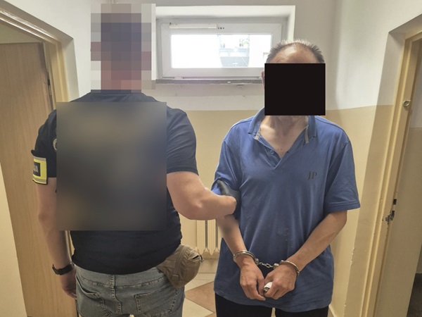 Policjant aresztujący podejrzanego w kajdankach.