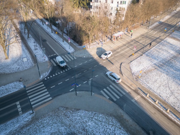 Widok z lotu ptaka na zaśnieżone skrzyżowanie z samochodami i pieszymi