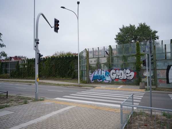 Przejście dla pieszych z sygnalizacją świetlną i ścianą pokrytą graffiti