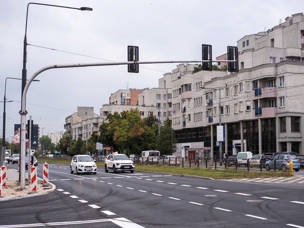 Scena uliczna miasta z samochodami na skrzyżowaniu w pobliżu nowoczesnych budynków mieszkalnych.