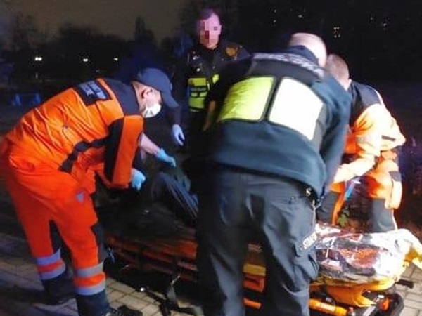 Ratownicy medyczni udzielają pomocy pacjentowi na noszach.