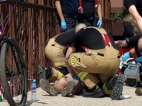 Ratownicy medyczni udzielają pomocy medycznej rowerzyście po wypadku.