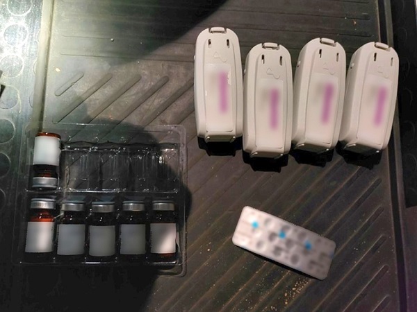 Fiolki z lekami, urządzenia elektroniczne i pilot zdalnego sterowania na teksturowanej powierzchni.