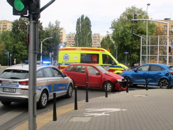Scena wypadku samochodowego z udziałem radiowozu, karetki pogotowia i uszkodzonych pojazdów.