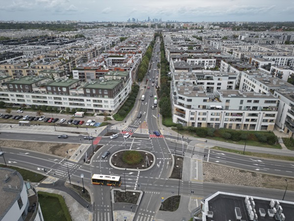 Widok z lotu ptaka na nowoczesne osiedle mieszkaniowe z rondem i przystankiem autobusowym.