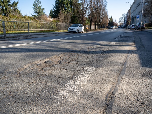 Bardzo zniszczona nawierzchnia asfaltowa z dziurami.