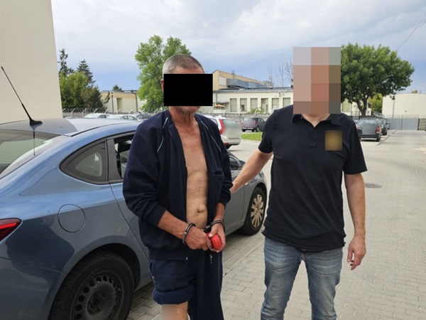 Policjant aresztujący mężczyznę w kajdankach.