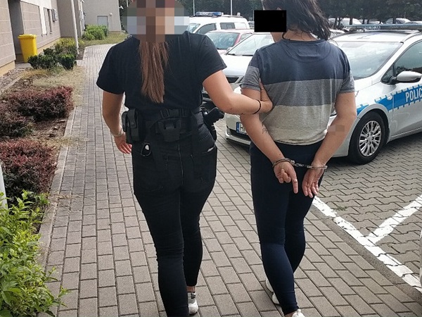 Policjant eskortujący kobietę w kajdankach