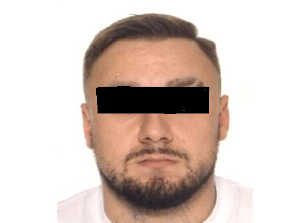 Zdjęcie mężczyzny z krótkimi brązowymi włosami i brodą oraz zasłoniętymi oczami.