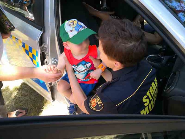 Policjant pocieszający dziecko w radiowozie. Straż Miejska.