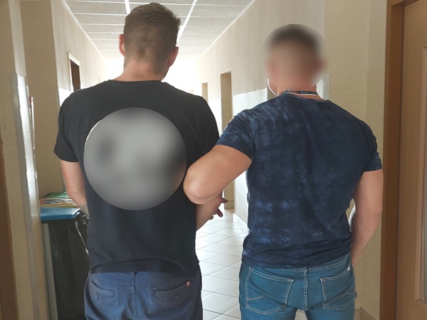 Dwóch mężczyzn idzie korytarzem, jeden obejmuje drugiego ramieniem.