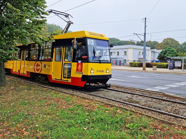 Żółty i czerwony tramwaj miejski nr 1408 na torach.