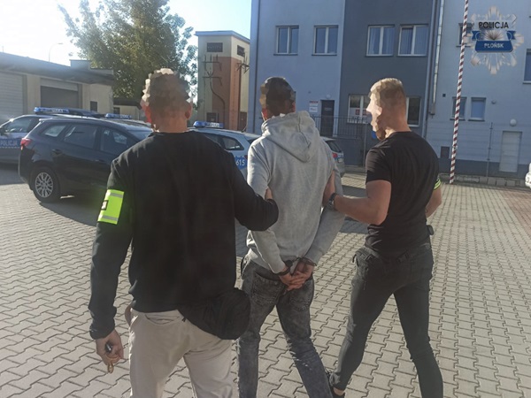 Policjanci zatrzymują podejrzanego w kajdankach.