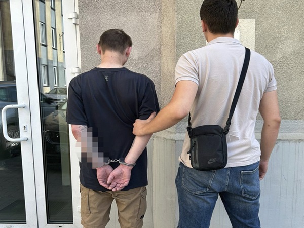 Policjant aresztujący podejrzanego w kajdankach.