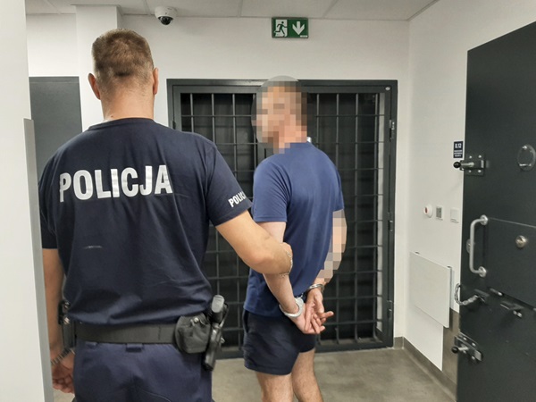 Policjant aresztujący podejrzanego, widoczne kajdanki. POLICJA.