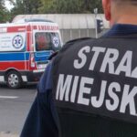 Funkcjonariusz Straży Miejskiej z karetką w tle