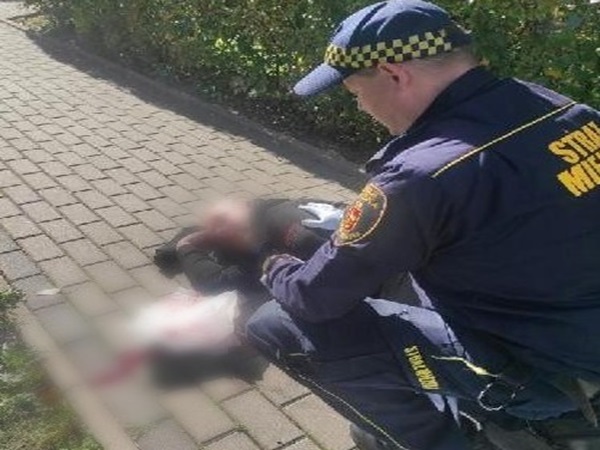 Ratownik udzielający pomocy osobie rannej na chodniku