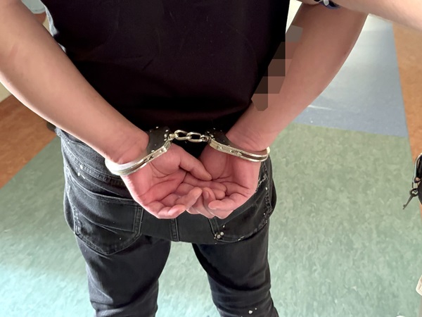 Osoba w kajdankach, widok z tyłu. Aresztowanie, egzekwowanie prawa.