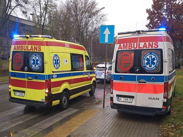Dwie polskie karetki pogotowia, oznaczone jako „Ambulans”, zaparkowane na ulicy miasta.