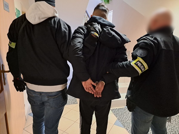 Policjanci zatrzymują podejrzanego. Widoczne kajdanki.