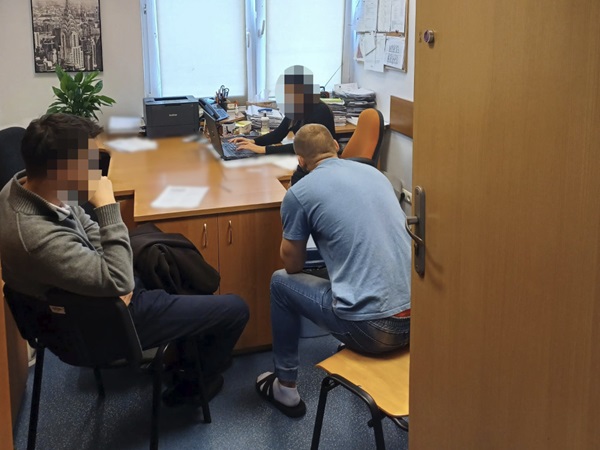 Trzy osoby siedzą w biurze podczas spotkania, jedna osoba przy komputerze.