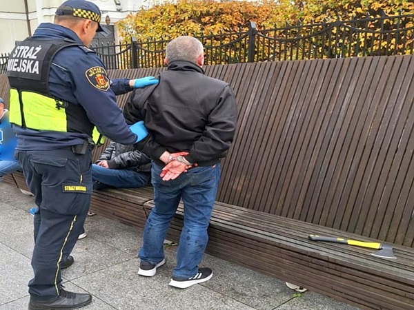 Policjant aresztujący mężczyznę na ławce. Na mundurze widoczna jest STRĄŻ MIEJSKA.