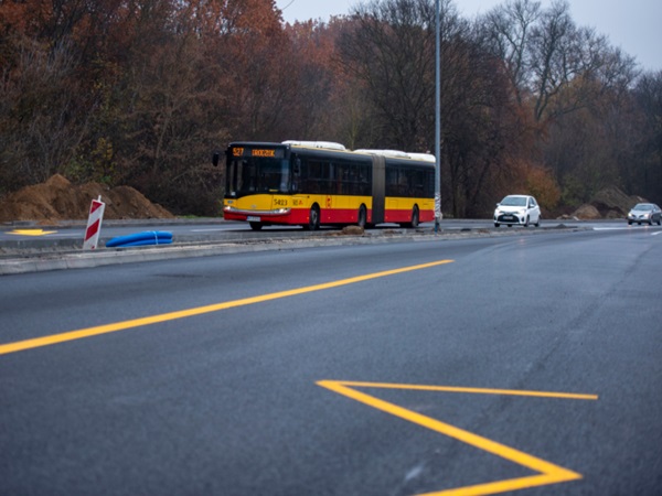 Żółty i czarny autobus miejski na nowo wyasfaltowanej drodze.