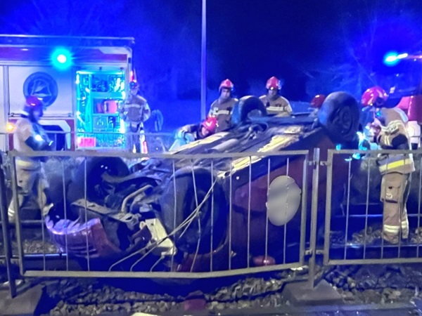 Ratownicy medyczni biorący udział w wypadku samochodowym na przejeździe kolejowym w nocy.