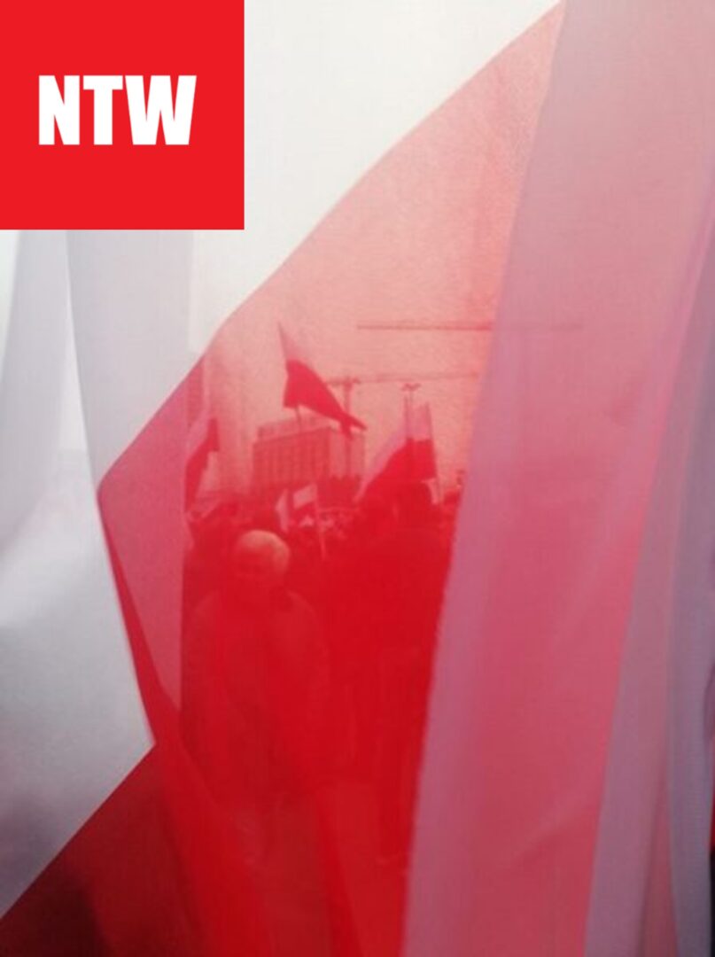 Czerwono-biały materiał rozłożony na tłumie trzymającym flagi; NTW.