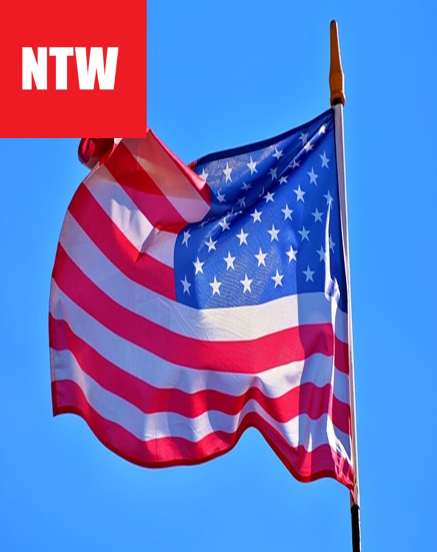 Amerykańska flaga powiewa dumnie na wietrze na tle czystego, błękitnego nieba.