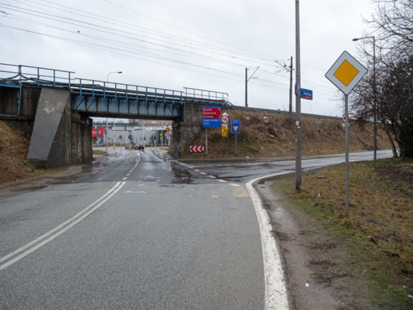 Mokra droga w kierunku mostu kolejowego, widoczne znaki drogowe