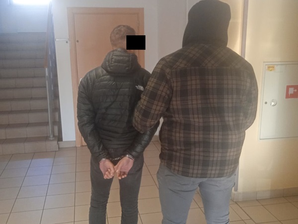 Mężczyzna w kajdankach eskortowany przez policjanta