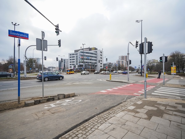 Skrzyżowanie ulicy Ostrobramskiej w Polsce, na którym widać sygnalizację świetlną, przejścia dla pieszych i rowerzystów.