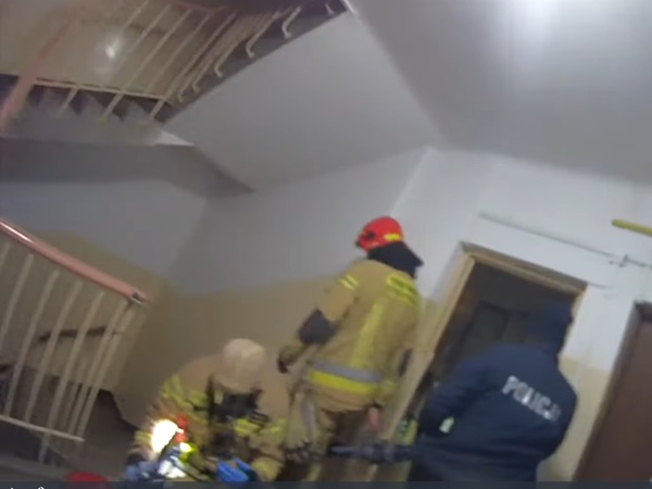 Strażacy i policjanci reagują na sygnał alarmowy dochodzący z klatki schodowej budynku.