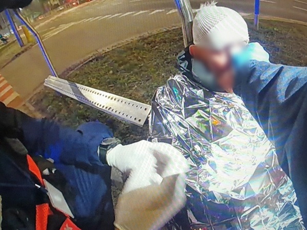 Udzielanie pierwszej pomocy osobie rannej owiniętej kocem termicznym.