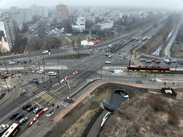 Widok z lotu ptaka na skrzyżowanie tramwajów i samochodów, ukazujący miejską infrastrukturę i transport.