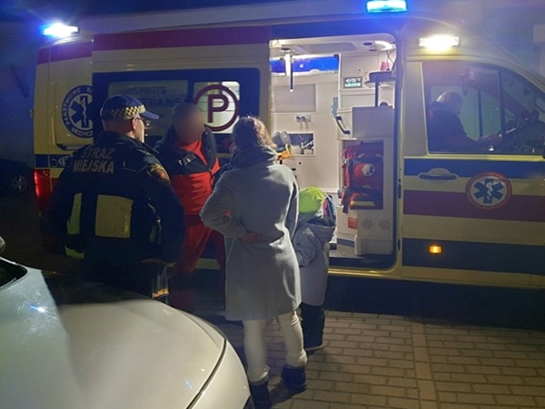 Ratownicy medyczni pomagają rodzinie w pobliżu karetki pogotowia.