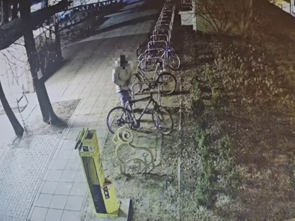 Nagrania z kamer pokazują mężczyznę kradnącego rower ze stojaka na rowery w nocy.